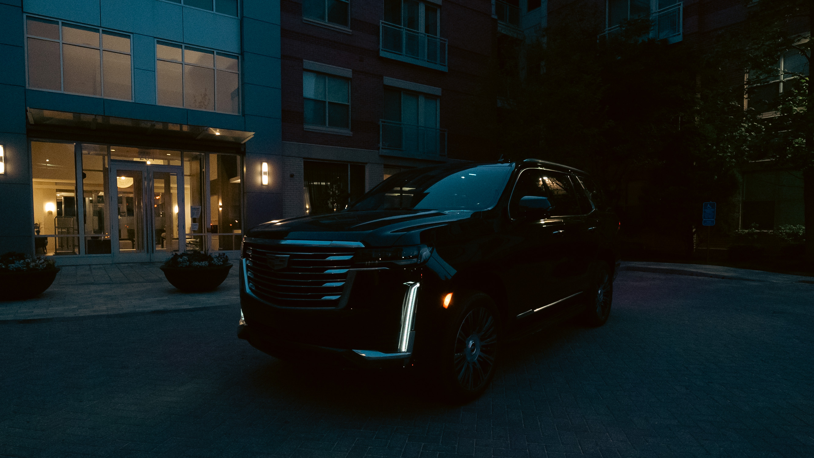 Cadillac Escalade parked at hotel entrance at night